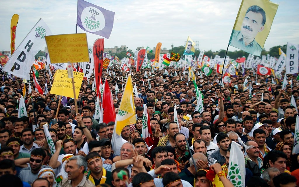 Supporters of Selahattin Demirtas, co-chair of the pro-Kurdish Peoples' Democratic Party, HDP, wave a poster of jailed Kurdish rebel leader Abdullah Ocalan, top right, as he addresses an election rally in Istanbul, Turkey, Saturday, May 30, 2015. Turkey will hold general election on June 7, 2015 and approximately 56 million Turkish voters are eligible to cast their ballots to elect the 550 members of the Grand National Assembly. (AP Photo/Emrah Gurel)