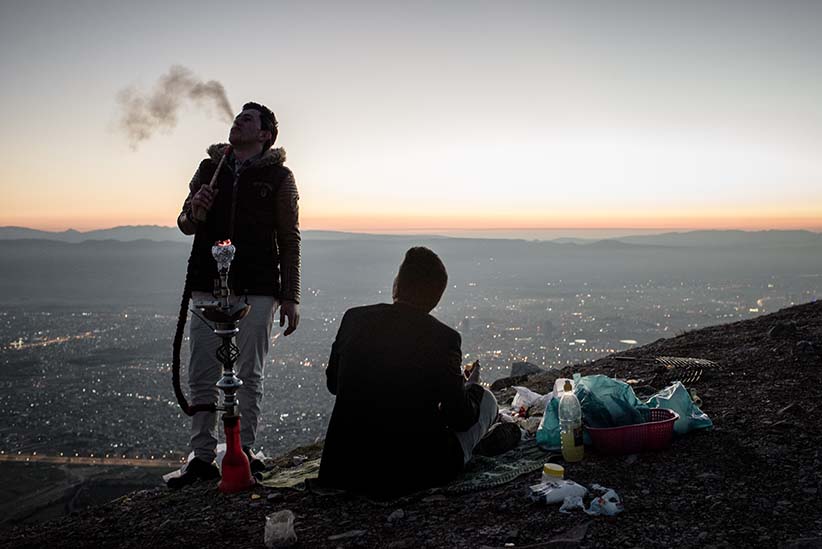 Hawkar, 21, and Muhammad, 18, smoke shisha and picnic on a mountain overlooking the city of Sulaymaniyah in Iraqi Kurdistan. When asked about the economic situation in Kurdistan, Hawker says "All the young people in Suli (Sulaymaniyah) are jobless and don't have money. If you go to the cafe. They don't have dinar in their pocket." (Photograph by Cengiz Yar)