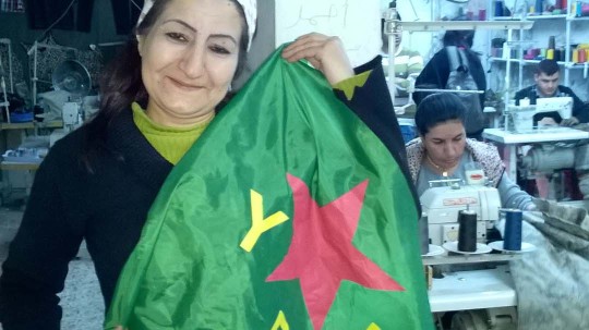 A Kurdish woman holds the standard (flag) of the Women's Protection Units (YPJ) Credit: Rahila Gupta